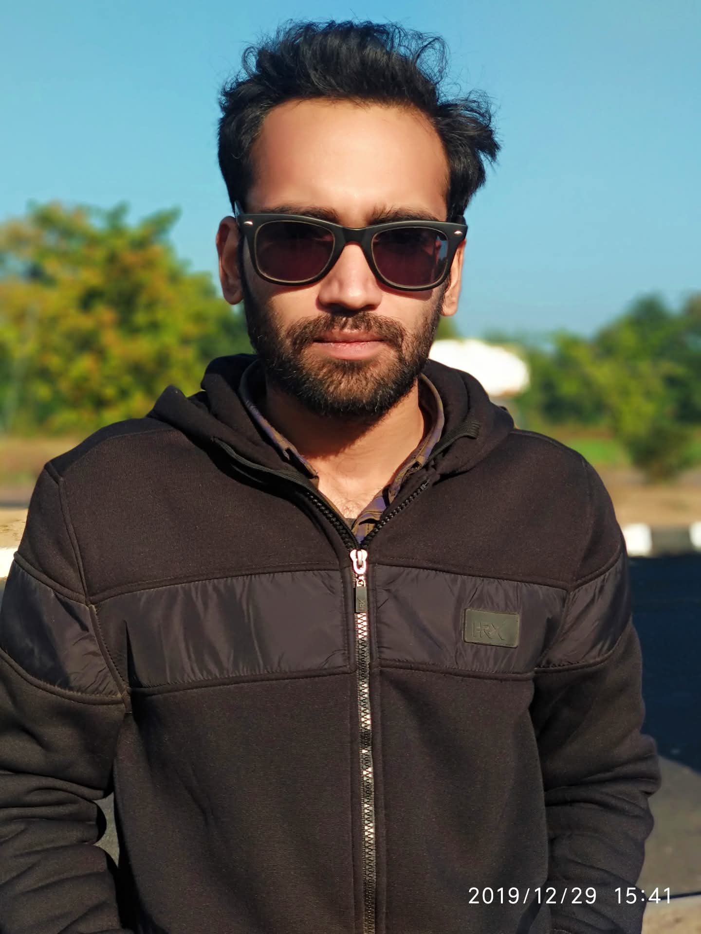 Shaleen Upadhayay smiling in a red plaid shirt and tortoise shell glasses